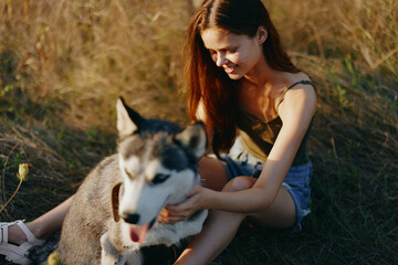 Woman sitting in field with dachshund dog smiling while spending time outdoors with dog friend