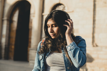 woman enjoying music with wireless headphones in an outdoor park at sunset. Concept of mental health, music and vacation.