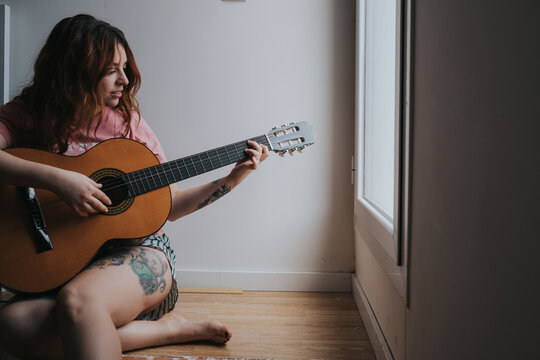 Young Smiling Woman With Guitar Sitting At Home