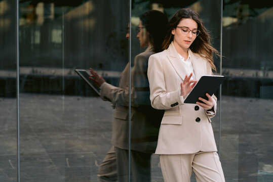 Businesswoman browsing tablet near office building in city
