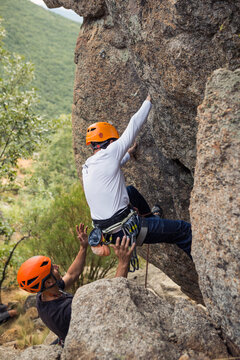 Hikers in equipment climbing mountain with support