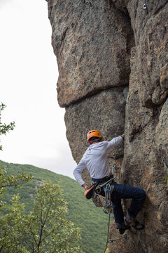 Climber in equipment climbing mountain helping with hand and leg