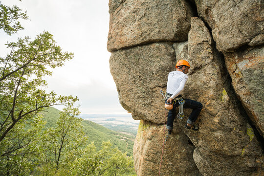 Climber in equipment climbing mountain helping with hand and leg
