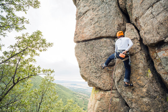 Climber in equipment climbing mountain helping with hand and leg