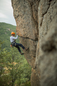 Climber in equipment climbing mountain helping with hand and leg