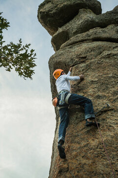 Climber in equipment climbing mountain helping with hand and leg