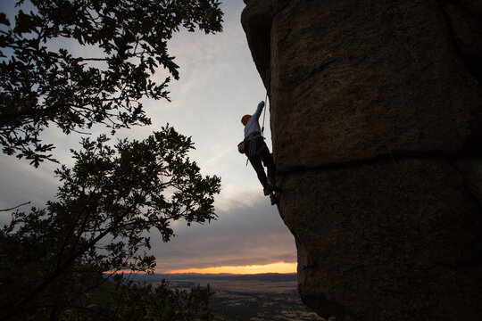 Climber in equipment climbing mountain helping with hand and leg