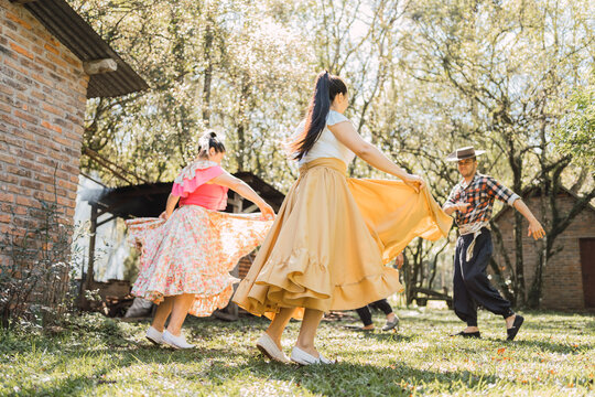 Unrecognizable ethnic friends dancing on lawn in garden