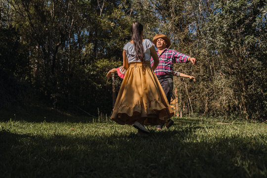 Unrecognizable ethnic friends dancing on lawn in garden