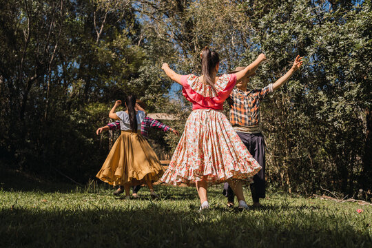 Unrecognizable ethnic friends dancing on lawn in garden