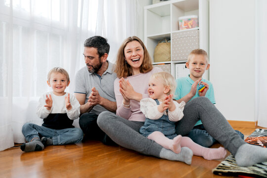 Cheerful family clapping hands on floor at home