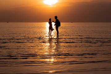 Couple talking in the sea during a golden sunset