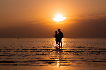 Man and woman talking on the beach during a golden sunset