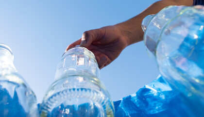 Man leaving a glass bottle in a blue recycling bin