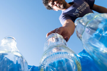 Man leaving a glass bottle in a blue recycling bin