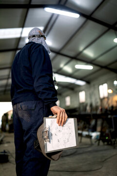 Concentrated mechanic in workshop writing notes in notepad