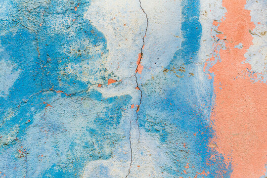 Old blue-pink wall covered with cracks