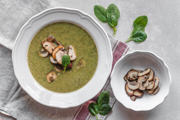 A plate with hot spinach soup, mushrooms and spinach leaves.