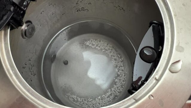 Interior view of stainless steel kettle with limescale and dirty water