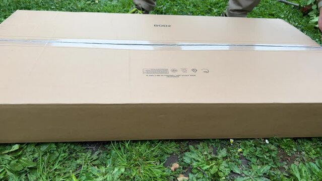 Side view of male hands unboxing cardboard parcel box