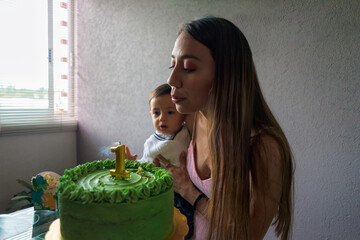 Ethnic mother with son blowing candle on cake