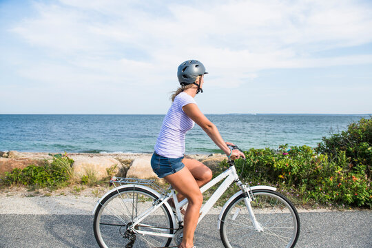 Young Woman biking by Cape Cod beaches coastal bike path