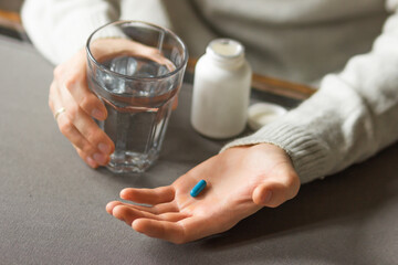 Man's hands holds a blue capsule and glass of water over the table, ready to take medicines. Health care concept. 