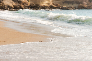 Mediterranean surf. Small waves roll on the shore. Sea foam on the beach.