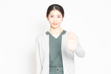 白背景の前でNGのジェスチャーをする女性
