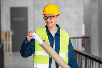 architecture, construction business and people concept - male architect in helmet with blueprint at office