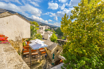 A small stone building with cafe overlooks a bridge and old town in the village of Mostar, Bosnia...