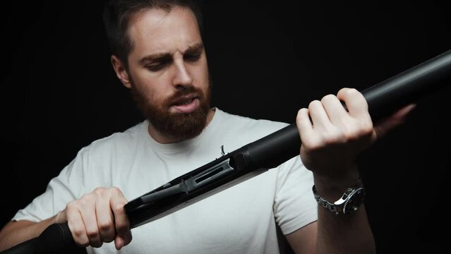 Close-up of a man examining a shotgun in his hands