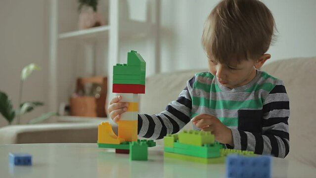 Child playing with colorful building plastic blocks constructor at home