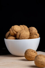 Walnuts in a white bowl on a wooden table