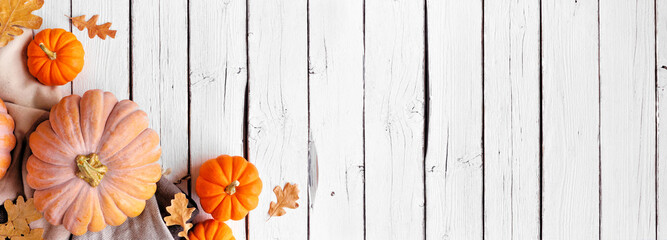 Cozy fall corner border with pumpkins, leaves and blanket. Overhead view on a white wood banner...