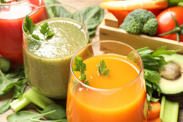 Delicious vegetable juices and fresh ingredients on wooden table, closeup