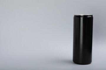 Black can of energy drink on light grey background. Space for text