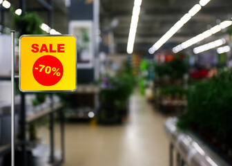 Sign with text SALE and 70 percent discount near gardening department in mall. Special promotion