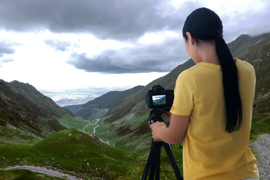 Photographer taking picture of beautiful mountains on cloudy day