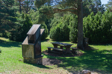 Picnic area and barbecues for rent in a green meadow with trees in a natural park in Lerida