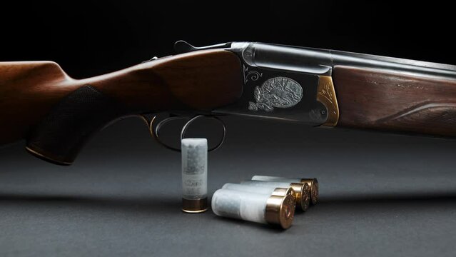 Close-up: a wooden hunting shotgun with cartridges on a table against a dark background