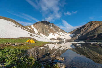Yellow tent camping beside a high alpine lake in Yukon Territory, Canada during summertime. 