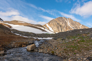 Running water, stream in northern Canada, Yukon Territory with large mountain background. 