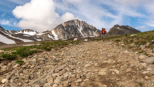 Man In Orange Jacket Hiking Through Yukon British Columbia Back Country Wilderness. 