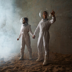 Astronauts in an empty colony on a deserted planet, a man and a woman in white futuristic...