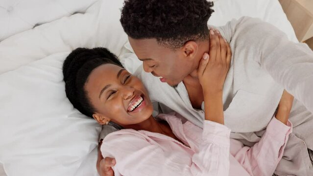 Love couple together in bedroom for kiss, hug and relax with romantic, intimate and playful affection at home. Above selfie of dating partners, young black people and care relationship on honeymoon