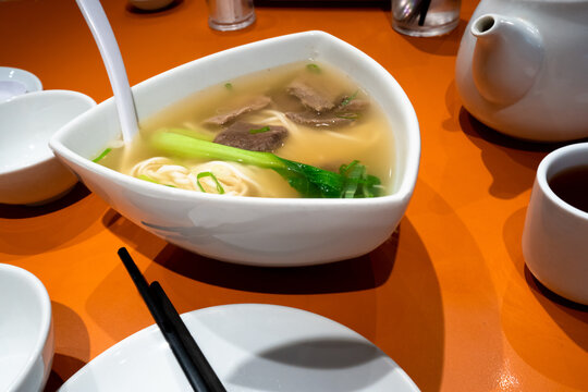 Bowl of beef mami for sharing served with hot tea at Chinese restaurant