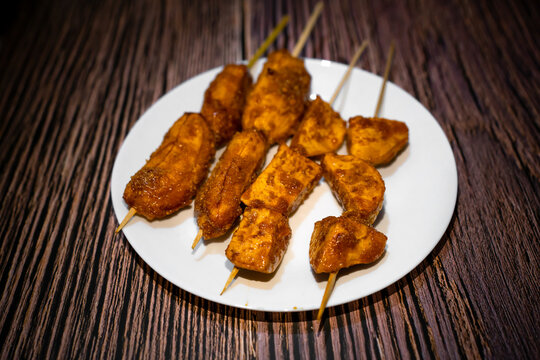 Caramelized banana and kamote que in a stick on white plate