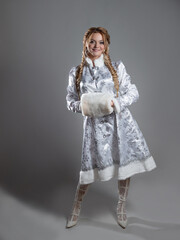 Snow maiden warms hands in the muff, a beautiful young woman in a fabulous fur coat of silver color, a character in a winter Christmas or New Year fairy tale.