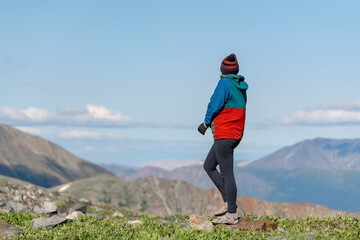 Hiker standing in alpine view area in Yukon Territory during summer time. 